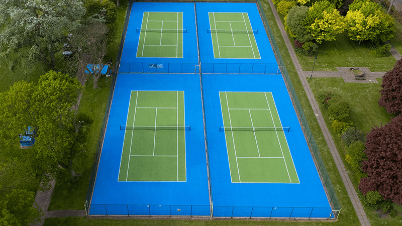 Tennis courts with grass and trees