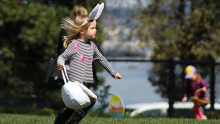 Image shows a child with bunny ears on an Easter egg hunt