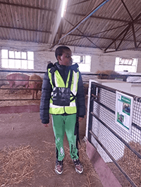 A person in a vest standing in a barn
