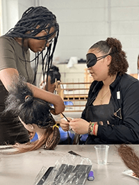 A person with a blindfold cutting a hair