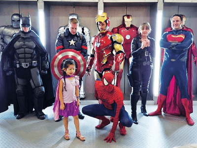 Photo of super heroes and a child at the Super Saturday event