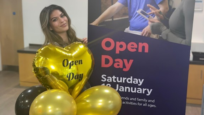 Member of staff standing with Leisure Centre Open Day 2026 banner
