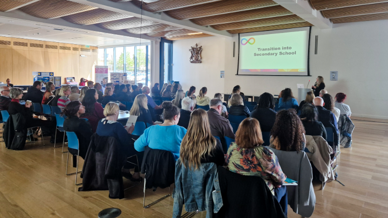 Audience attentively listening to a speaker presenting 'Transition into Secondary School' in the Council Chamber at Bexley Civic Offices.