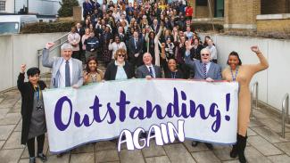 Image of staff and Councillors celebrating an outstanding Ofsted report with a banner that says 'Outstanding Again'
