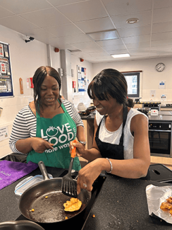 Two people in aprons cooking in a kitchen