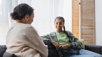 Two people sitting on a couch having a friendly conversation.