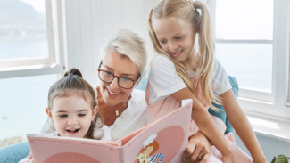 Smiling foster carer reading a storybook with two girls