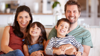 Smiling foster family sitting together on a couch at home