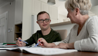 Two people looking at each other with paperwork in front of them.