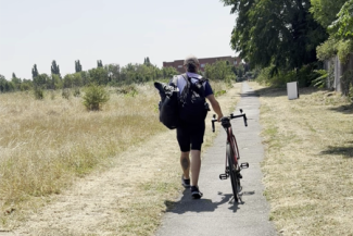 Image of a cyclist walking with their bike within an open space