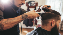 Image shows a barbar cutting a man's hair