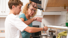 Image of a adult helping a teenager cook a meal