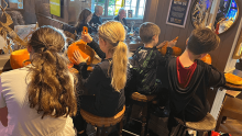 Children sitting at a table carving pumpkins