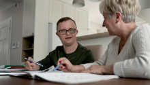 Two people looking at each other with paperwork in front of them.